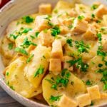 A bowl of crock pot scalloped potatoes with parsley on it