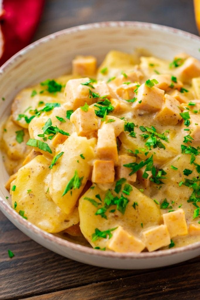 A bowl of crock pot scalloped potatoes with parsley on it