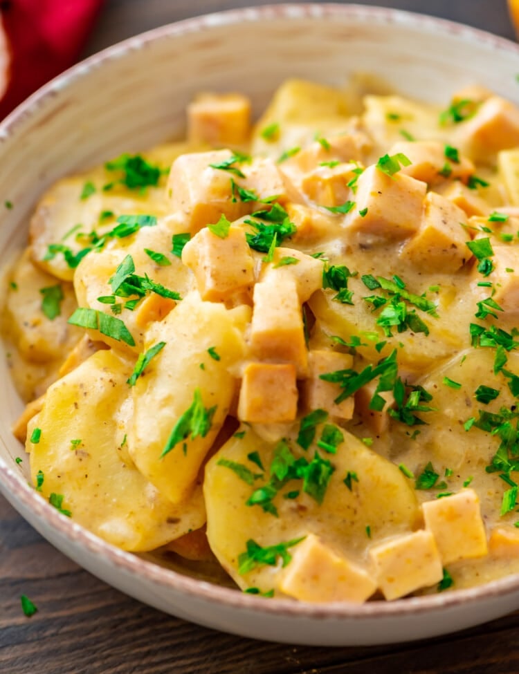 A bowl of crock pot scalloped potatoes with parsley on it