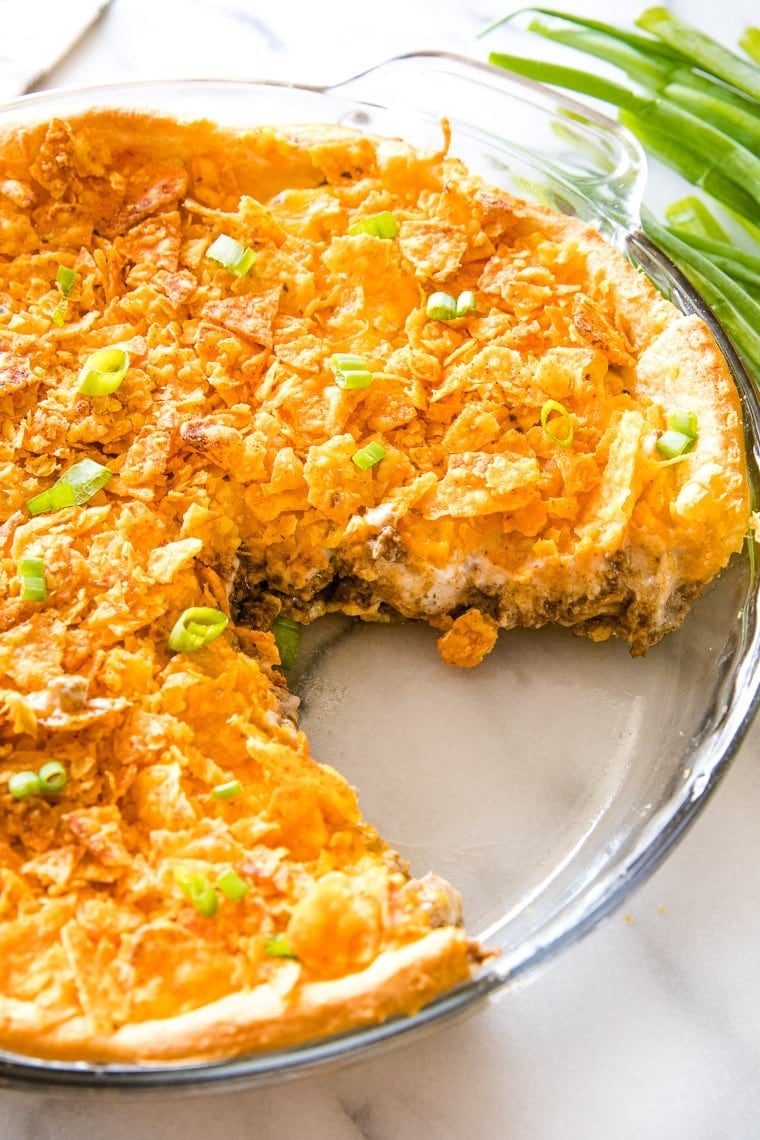 Taco Pie in glass pie dish with a slice gone.