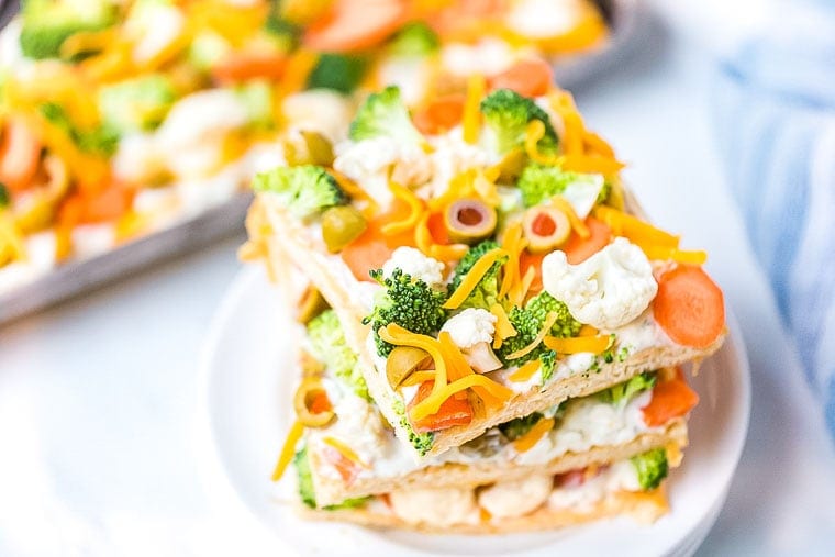 Three pieces of Vegetable Pizza stacked on white plate.