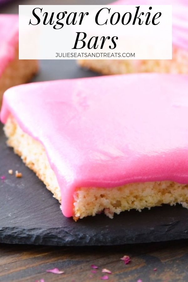 Sugar cookie bars with pink frosting on a slate tray