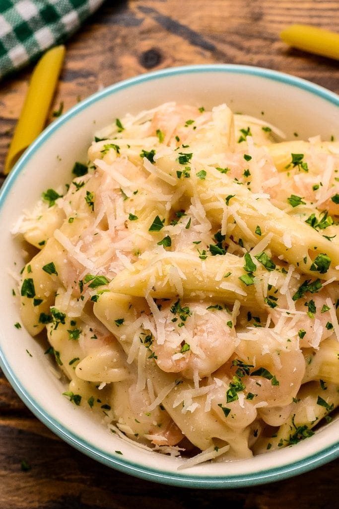 Overhead close up of a bowl of shrimp pasta with parsley garnish