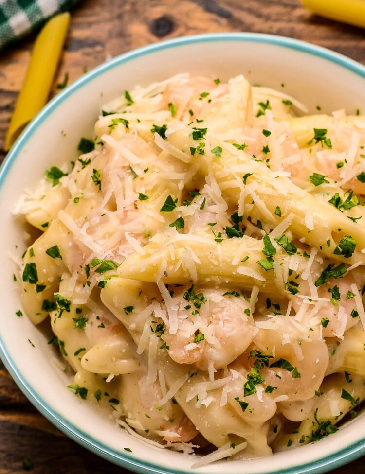 Overhead close up of a bowl of shrimp pasta with parsley garnish