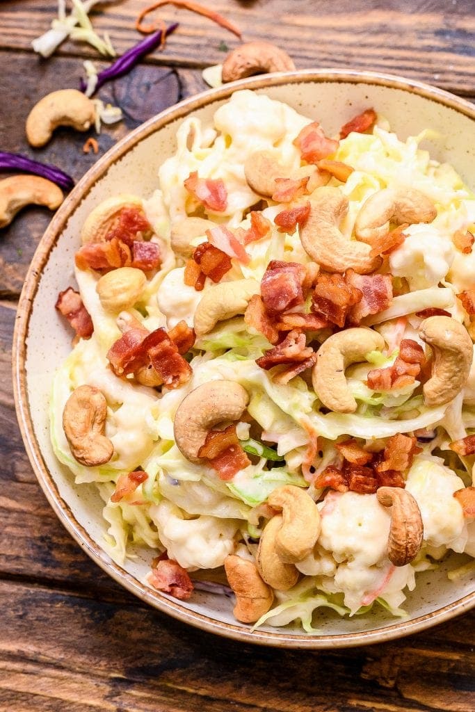 Overhead picture of cashew coleslaw in bowl topped with bacon and cashews