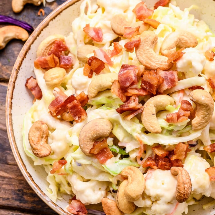 Overhead picture of cashew coleslaw in bowl topped with bacon and cashews