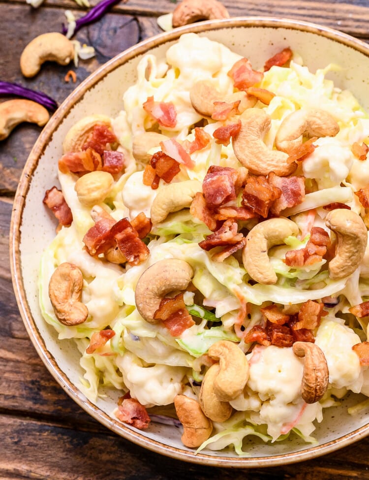 Overhead picture of cashew coleslaw in bowl topped with bacon and cashews