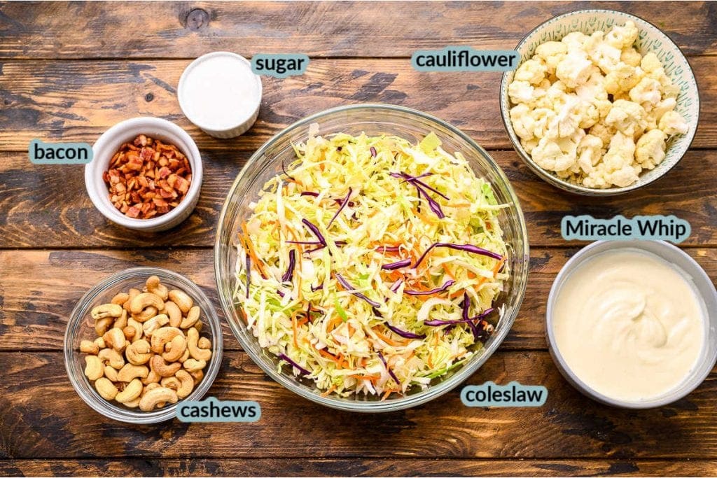 Overhead image showing coleslaw mix cashews miracle whip cauliflower bacon and sugar