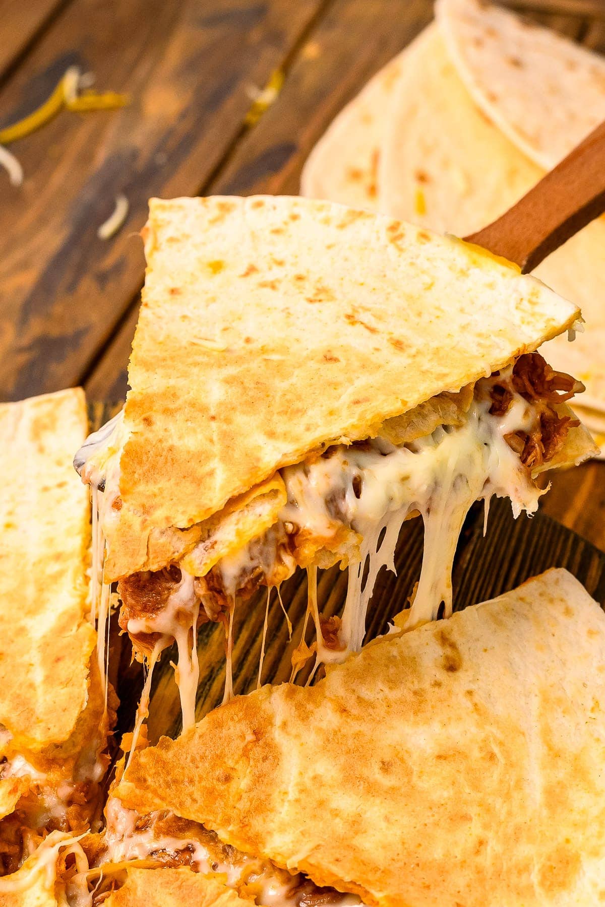 Piece of quesadilla being lifted and melted cheese pulling