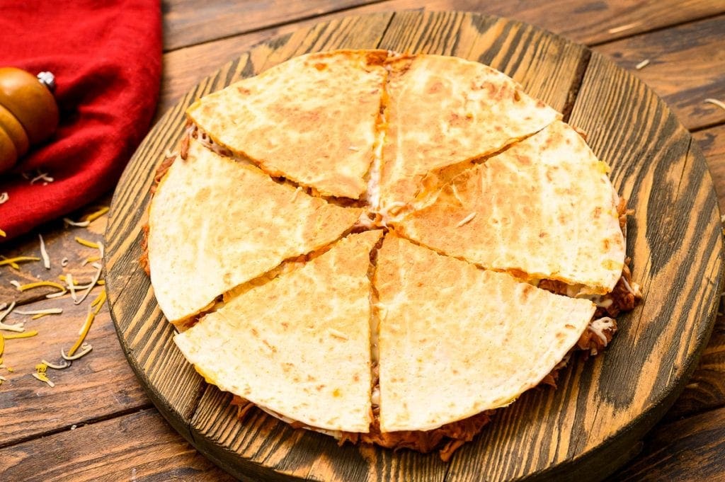 Quesadilla on wood cutting board cut into triangles