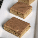 Three cinnamon frosted zucchini bars on a white plate