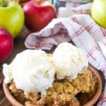 Apple Crisp Recipe on brown plate topped with two scoops of vanilla ice cream