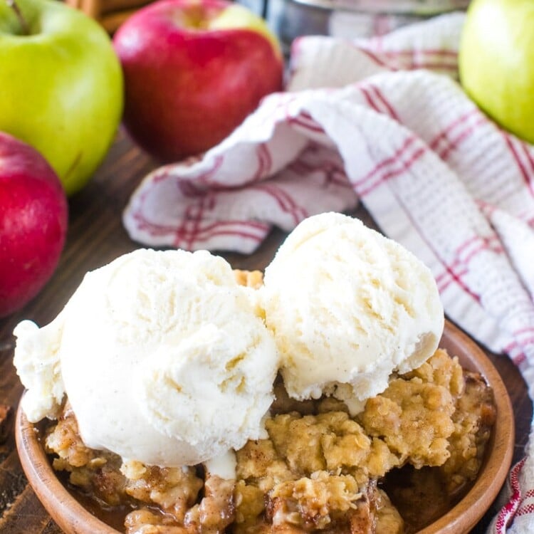 Apple Crisp Recipe on brown plate topped with two scoops of vanilla ice cream