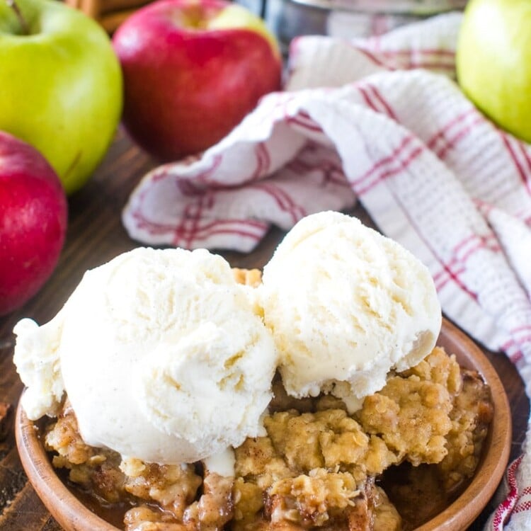 Apple Crisp Recipe on brown plate topped with two scoops of vanilla ice cream
