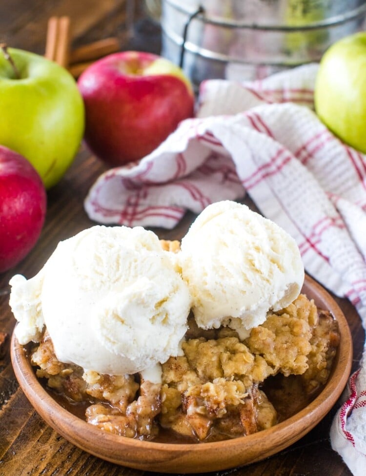 Apple Crisp Recipe on brown plate topped with two scoops of vanilla ice cream