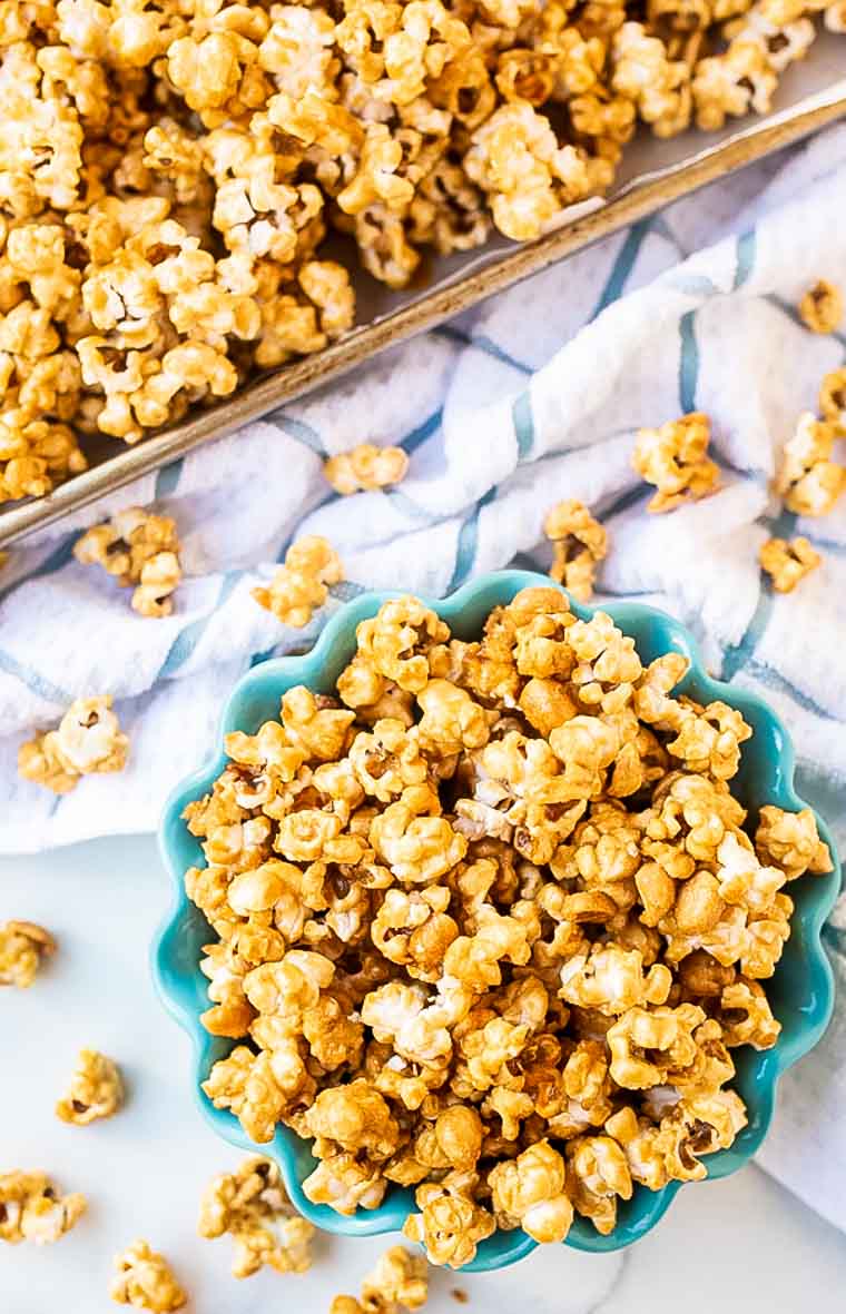 Baking sheet and bowl filled with caramel corn in an overhead image.