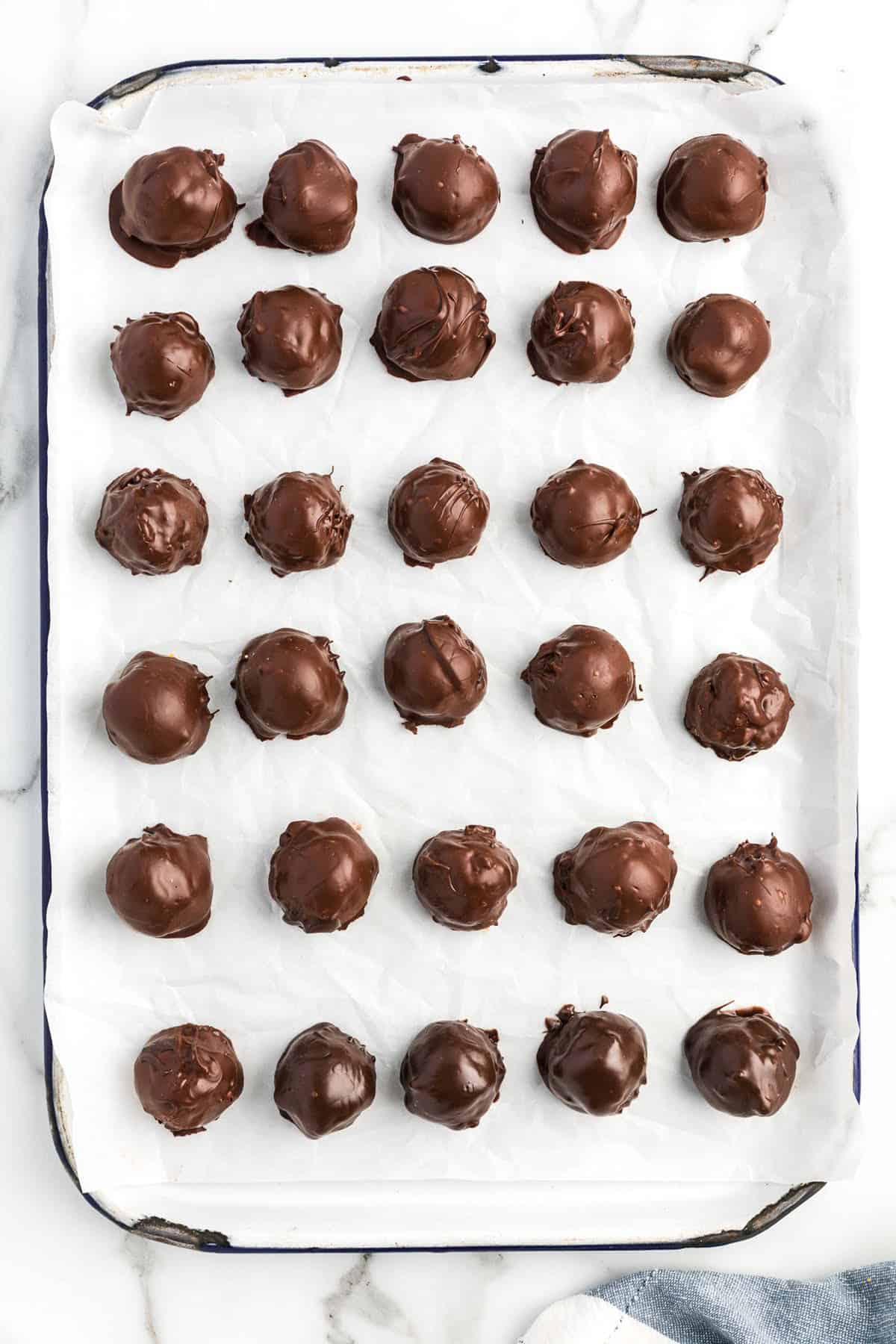 Chocolate dipped peanut butter balls on baking sheet