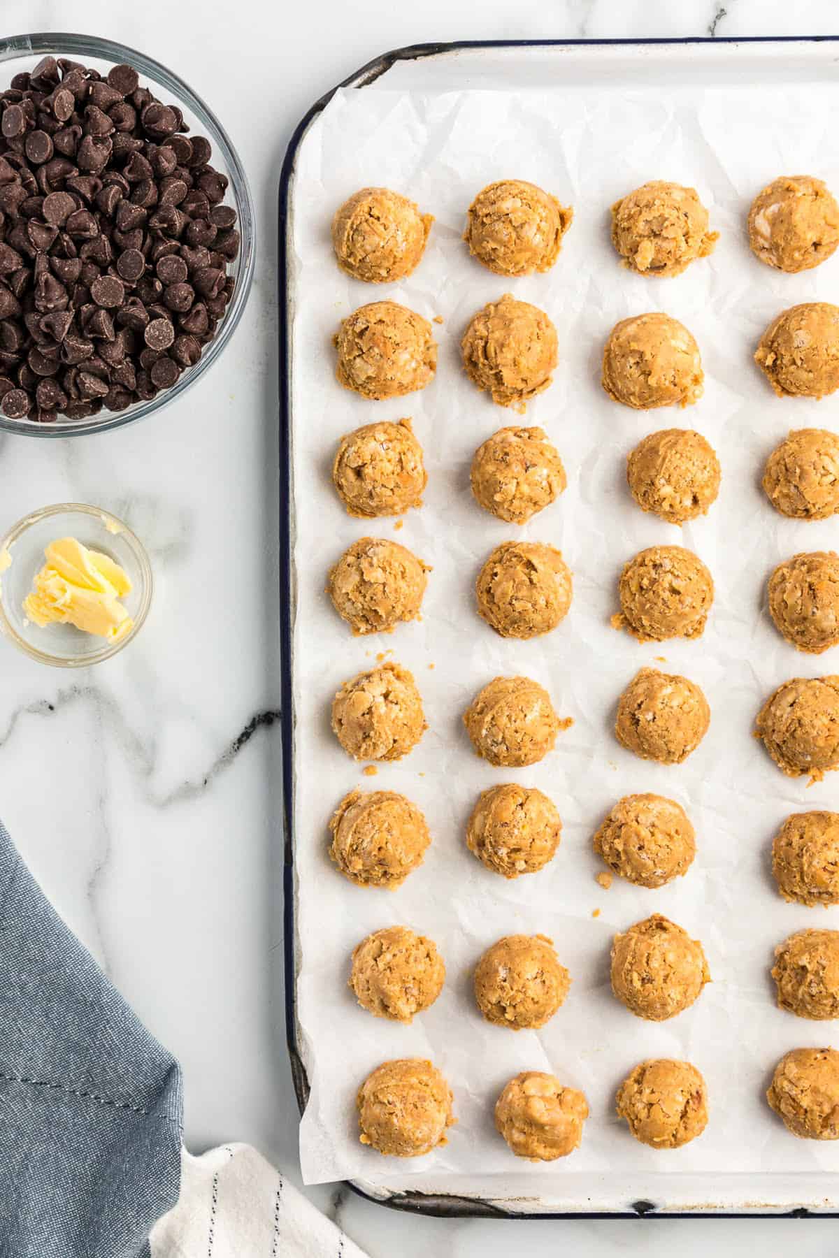 Baking sheet lined with parchment paper with peanut butter balls on it