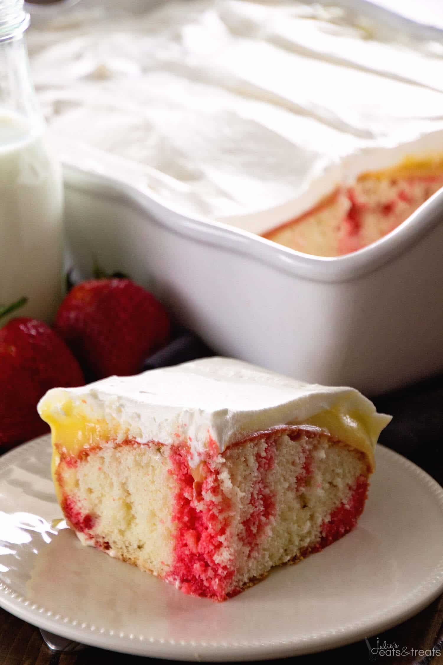 Strawberry Poke Cake dished up on a white plate with strawberries and cake in the background.