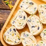 Overhead image of Wooden plate with sliced pinwheels on it