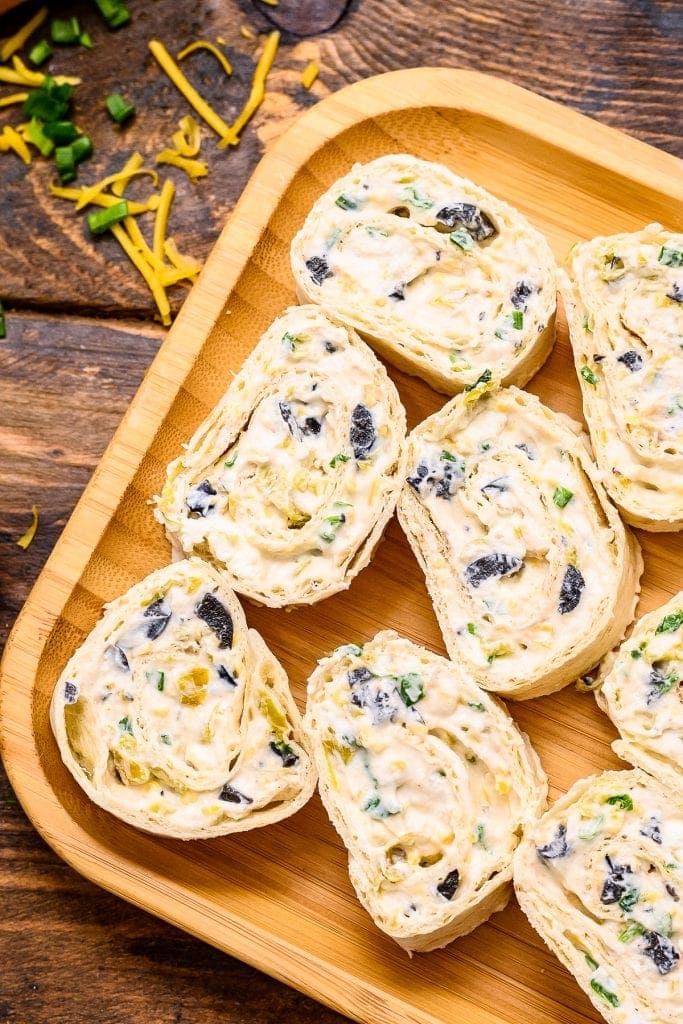 Overhead image of Wooden plate with sliced pinwheels on it