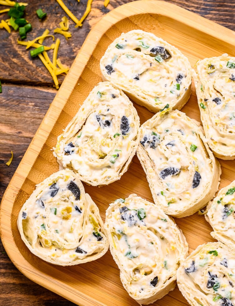 Overhead image of Wooden plate with sliced pinwheels on it