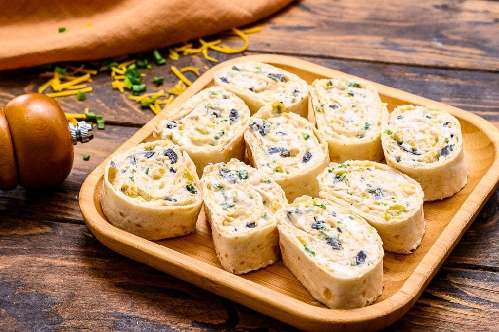 Wood background with sliced tortilla pinwheels on a wooden plate