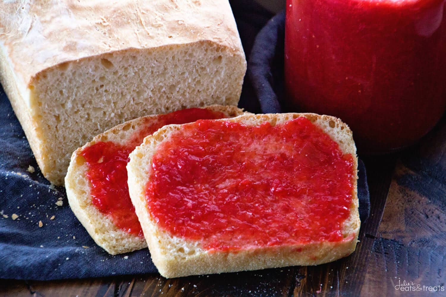 Slices of English Muffin bread with strawberry rhubarb jam on it and jar of jam in background