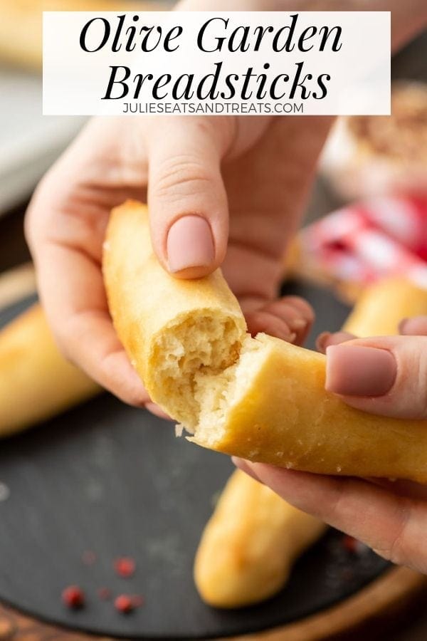 Hands tearing an olive garden breadstick in half