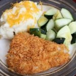 A french's crunchy cheddar onion chicken breast on a plate with mashed potatoes and zucchini