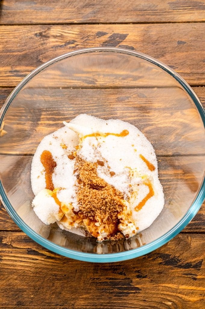 Glass bowl with cream cheese, brown sugar, vanilla, sugar before mixing