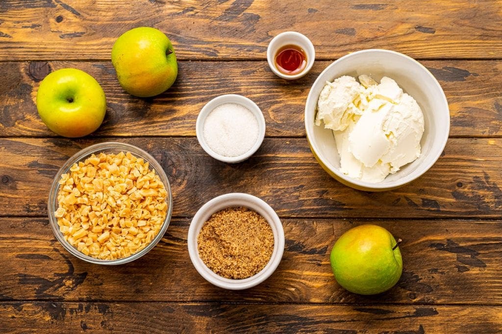 Ingredients in bowls including bowls of brown sugar, toffee pieces, sugar, brown sugar, vanilla and cream cheese.