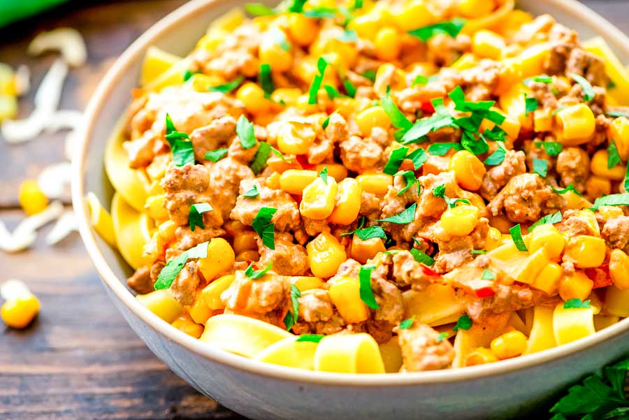 A bowl of taco stroganoff served over egg noodles and garnished with parsley