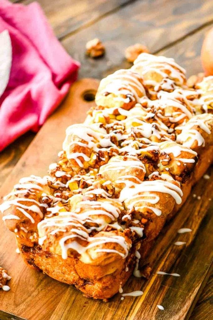 Apple Pull Apart Bread on cutting board topped with a powdered sugar icing