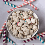 Overhead image of a white bowl full of cake batter puppy chow surrounded by colorful straws