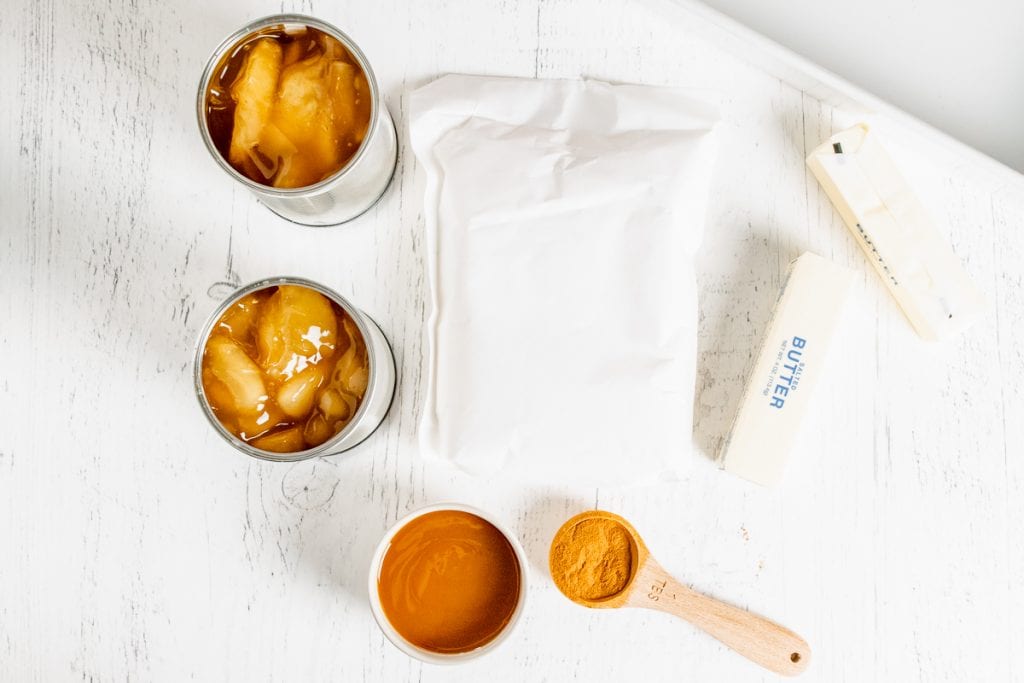 White background with apple filling, caramel sauce, cinnamon, cake mix and butter to make dump cake