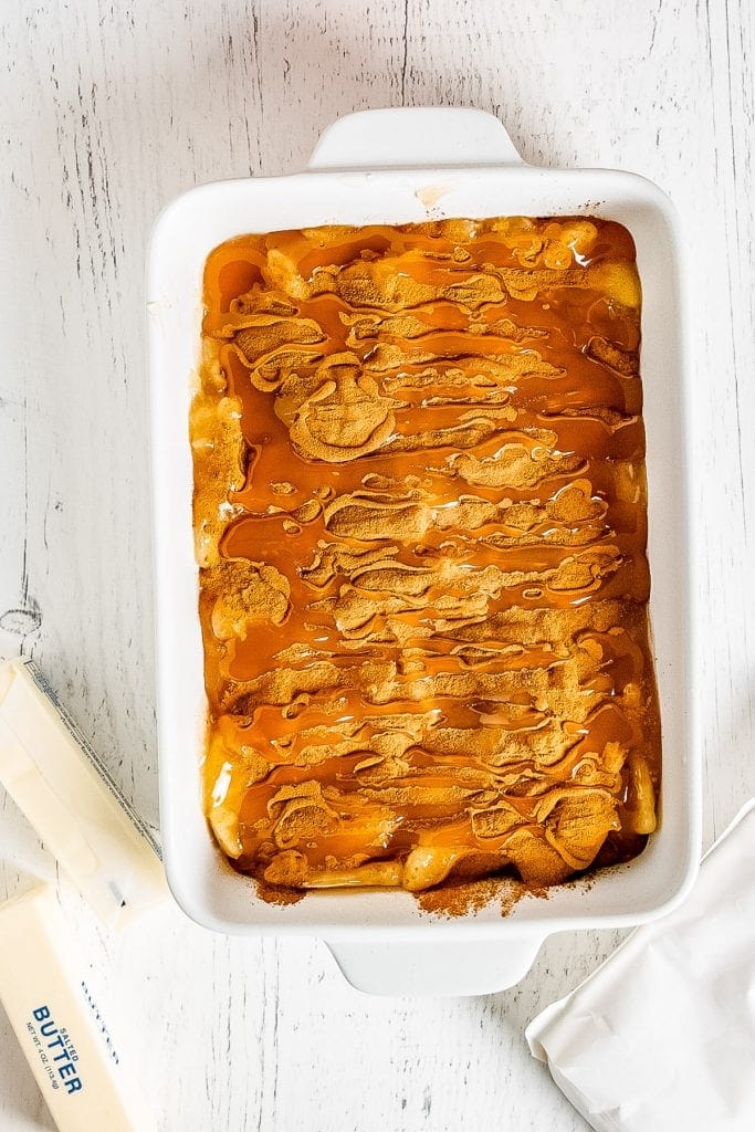 Caramel poured overlay of cinnamon in white baking dish for cake