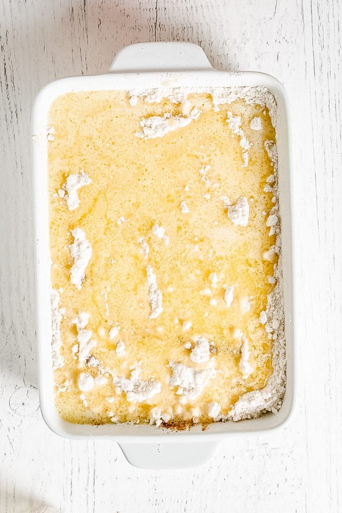 Butter poured over cake mix in white baking dish for cake