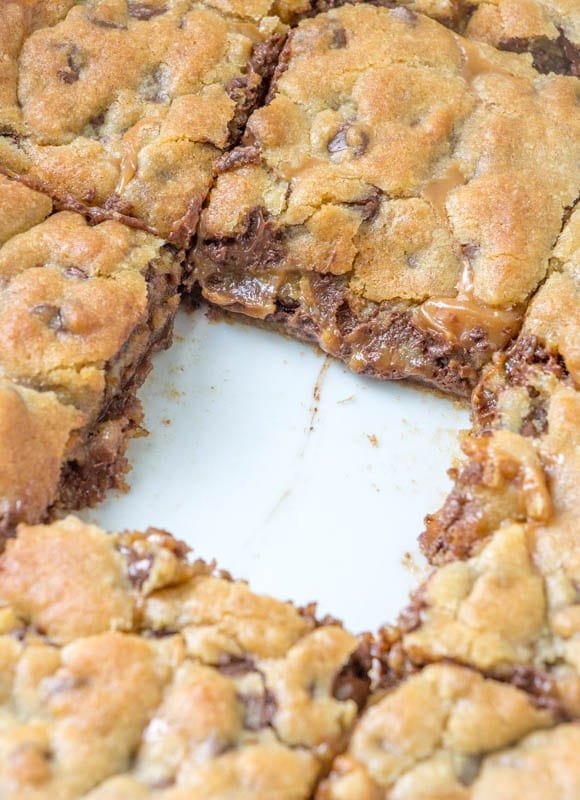 A pan of sliced caramel cookie bars with one missing right from the middle!