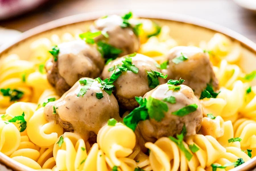 close up swedish meatballs served over noodles