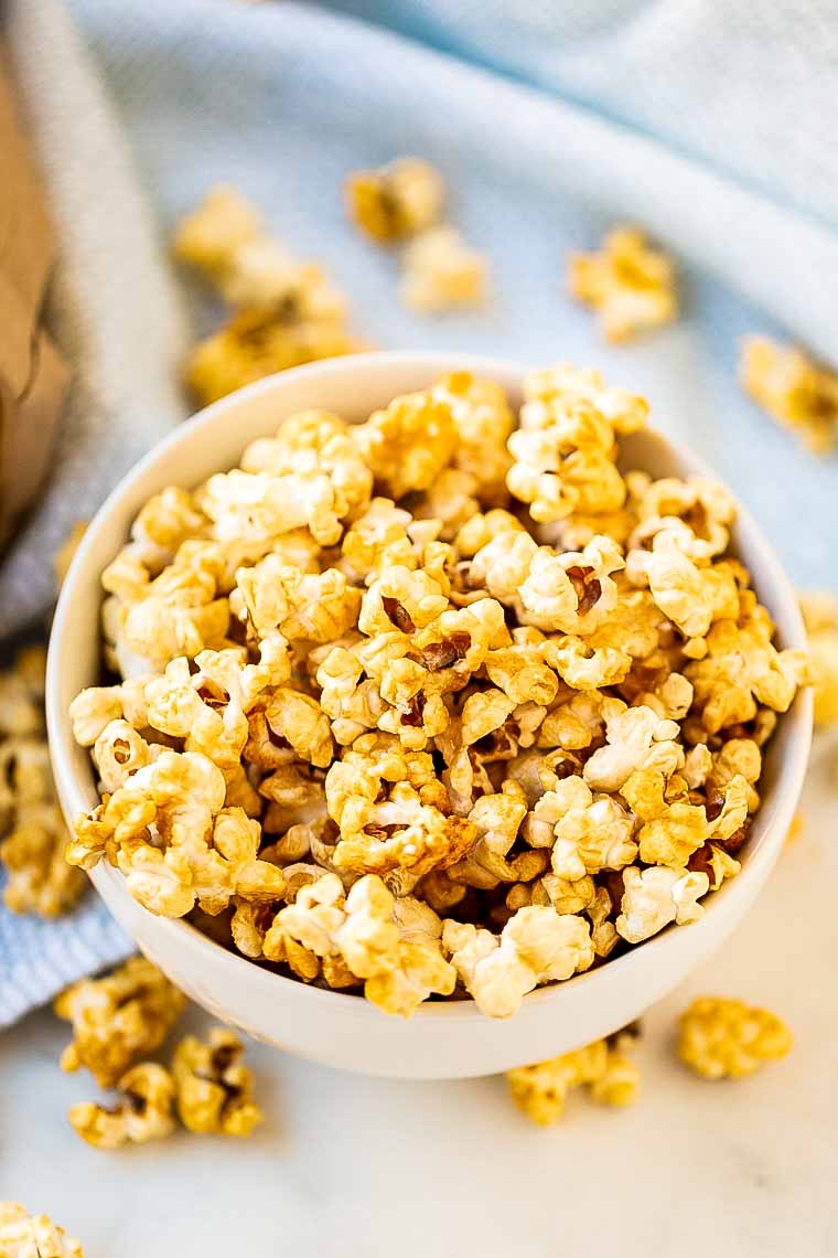 Bowl holding caramel corn with it spilled beside it.