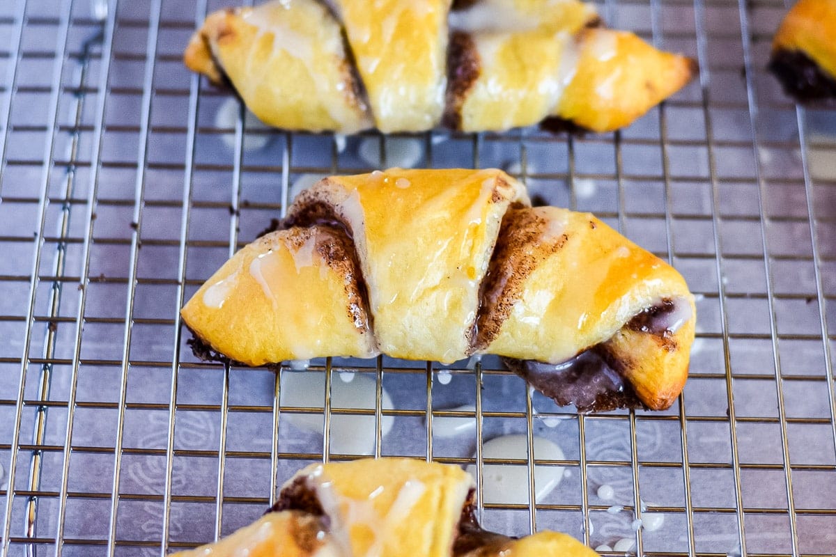 Cinnamon Crescent Rolls on a wire rack with glaze on them