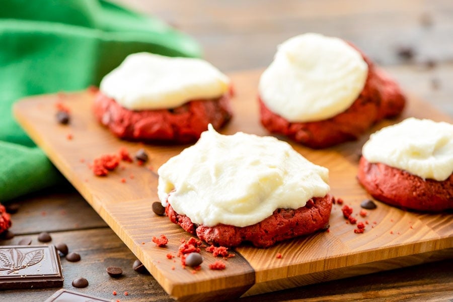Frosted Red Velvet Cookies on wood cutting board