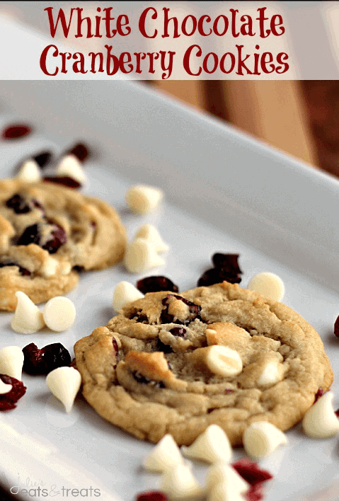White chocolate cranberry cookies on a white tray with white chocolate chips and dried cranberries