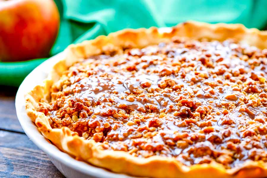 Apple Crumb Pie in a white baking dish drizzled with caramel.