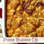 A white casserole dish of pizza bubble up on a wood cutting board