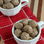 Two white mugs of crock pot meatball stroganoff over pasta sitting on a red towel