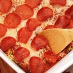 A white baking dish of pizzetti with a wood spoon about to scoop some out