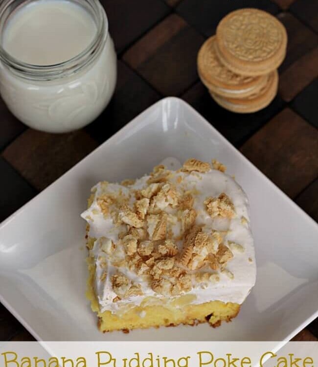 A piece of banana pudding poke cake on a square white plate next to a stack of golden Oreos and a glass jar of milk