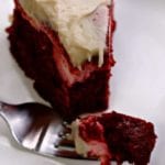 A slice of red velvet cheesecake bundt cake on a white square plate with a fork holding a bite off the end